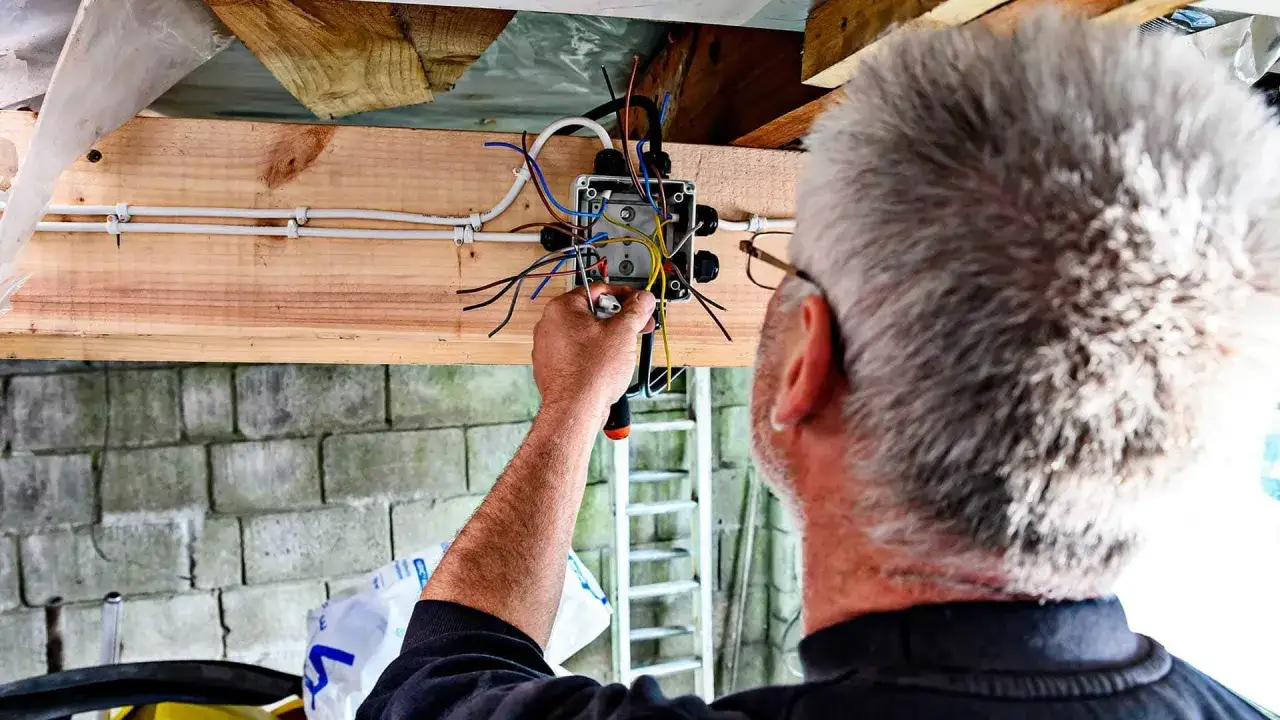 elektryk montujący instalację elektryczną w ścianie